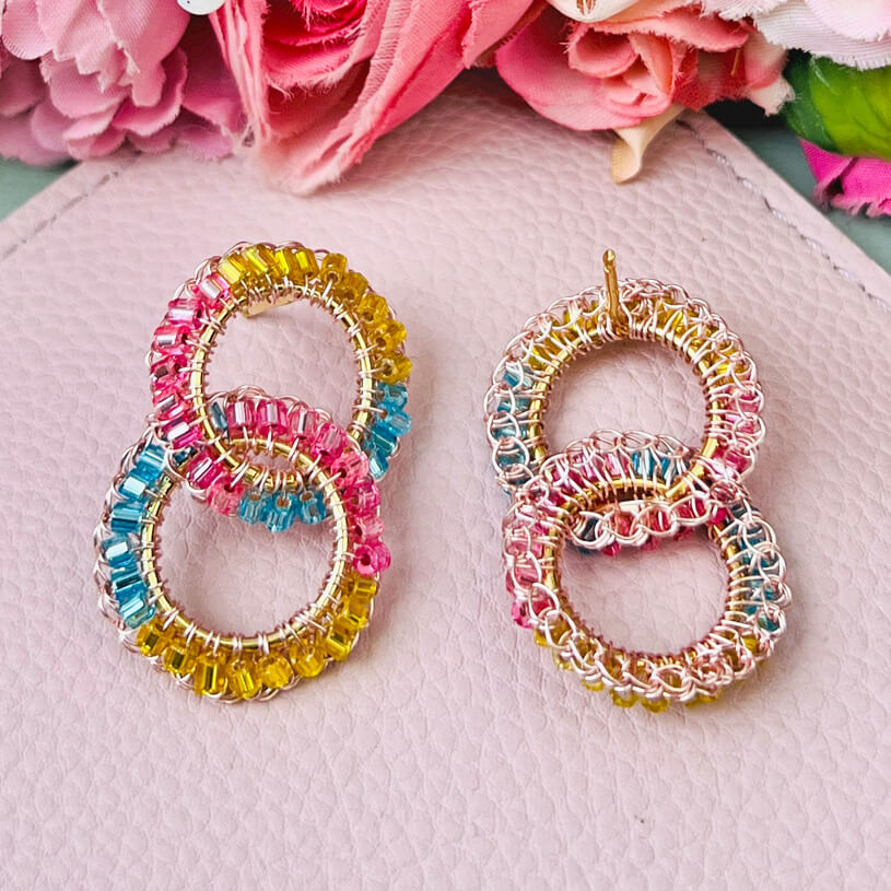 Schöne sommerliche Ohrringe aus geflochtenen Drähten mit glitzernden Perlen